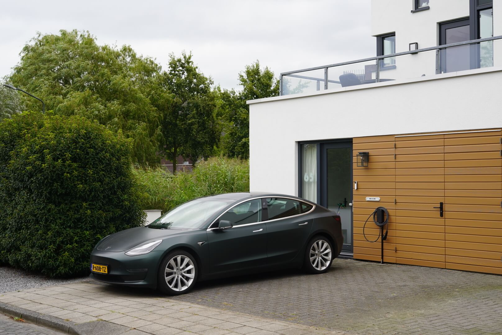 A Tesla car and amina charger in front of a house
