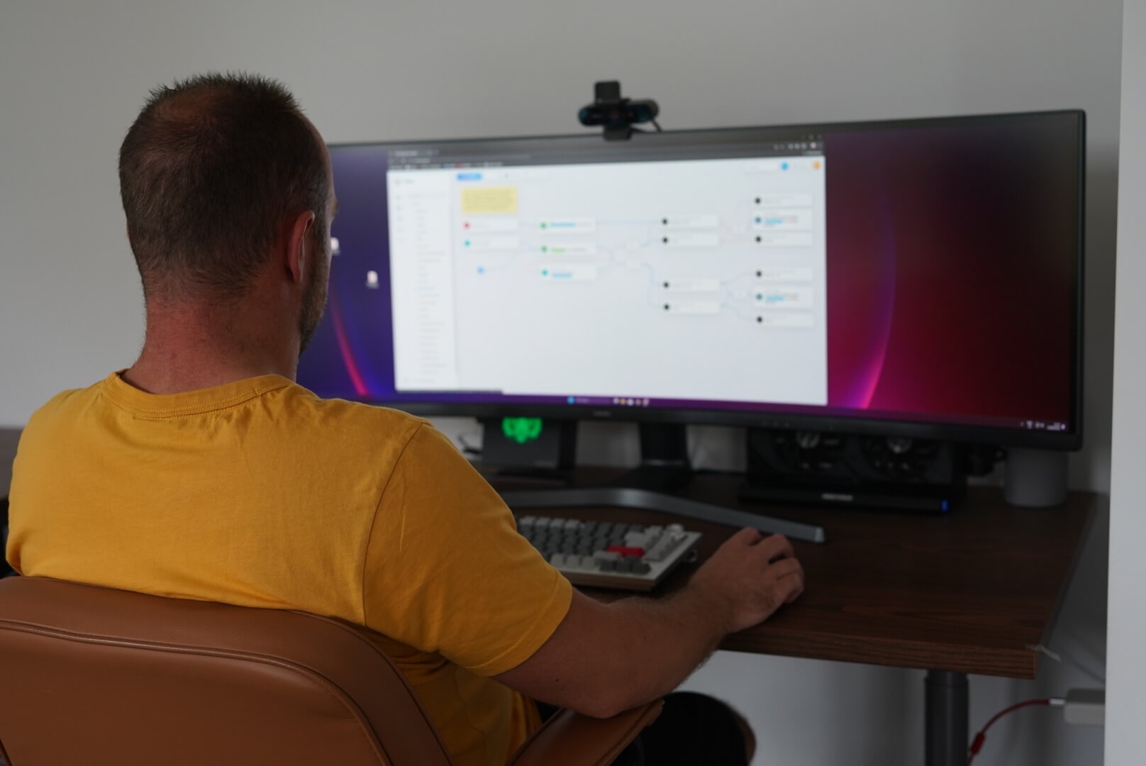 A person in front of PC monitor that displays a Flow in the Homey Web App
